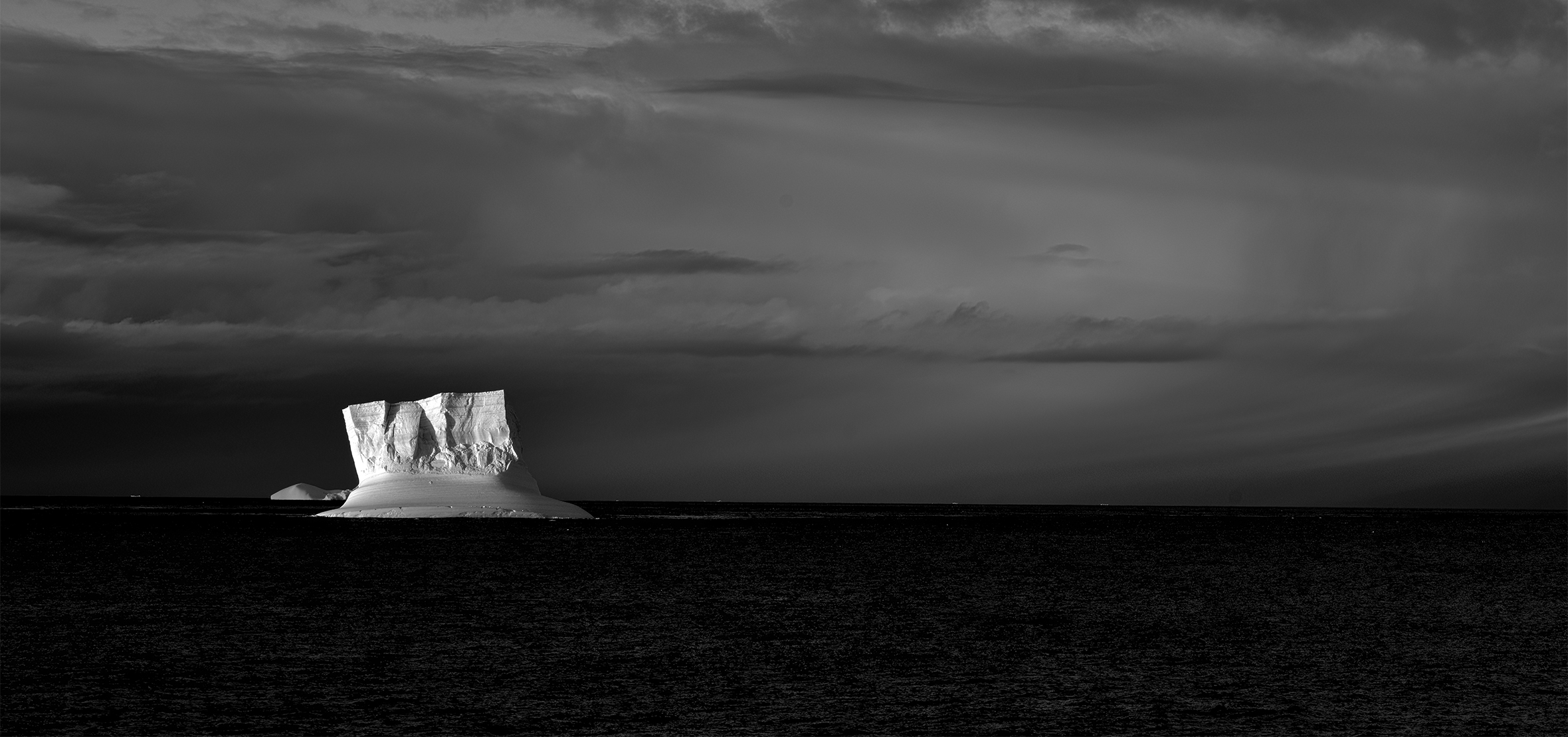 An iceberg, stark against the water and the cloudy skies, seen on an expedition to Antarctica.