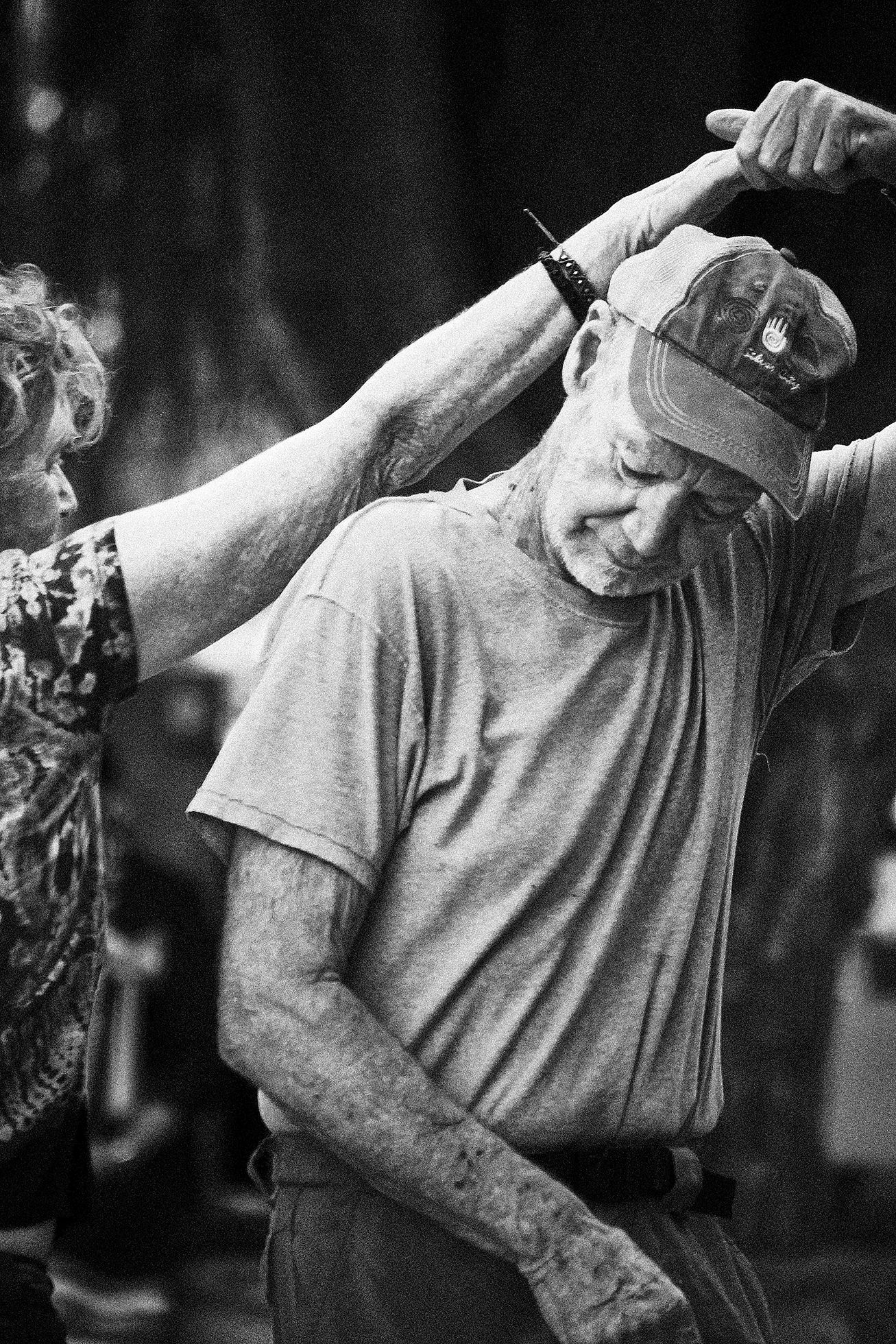 An older couple dance together in Gough Park in Silver City, New Mexico, on an evening of free music. The woman passes behind the man while their hands are joined above their heads.