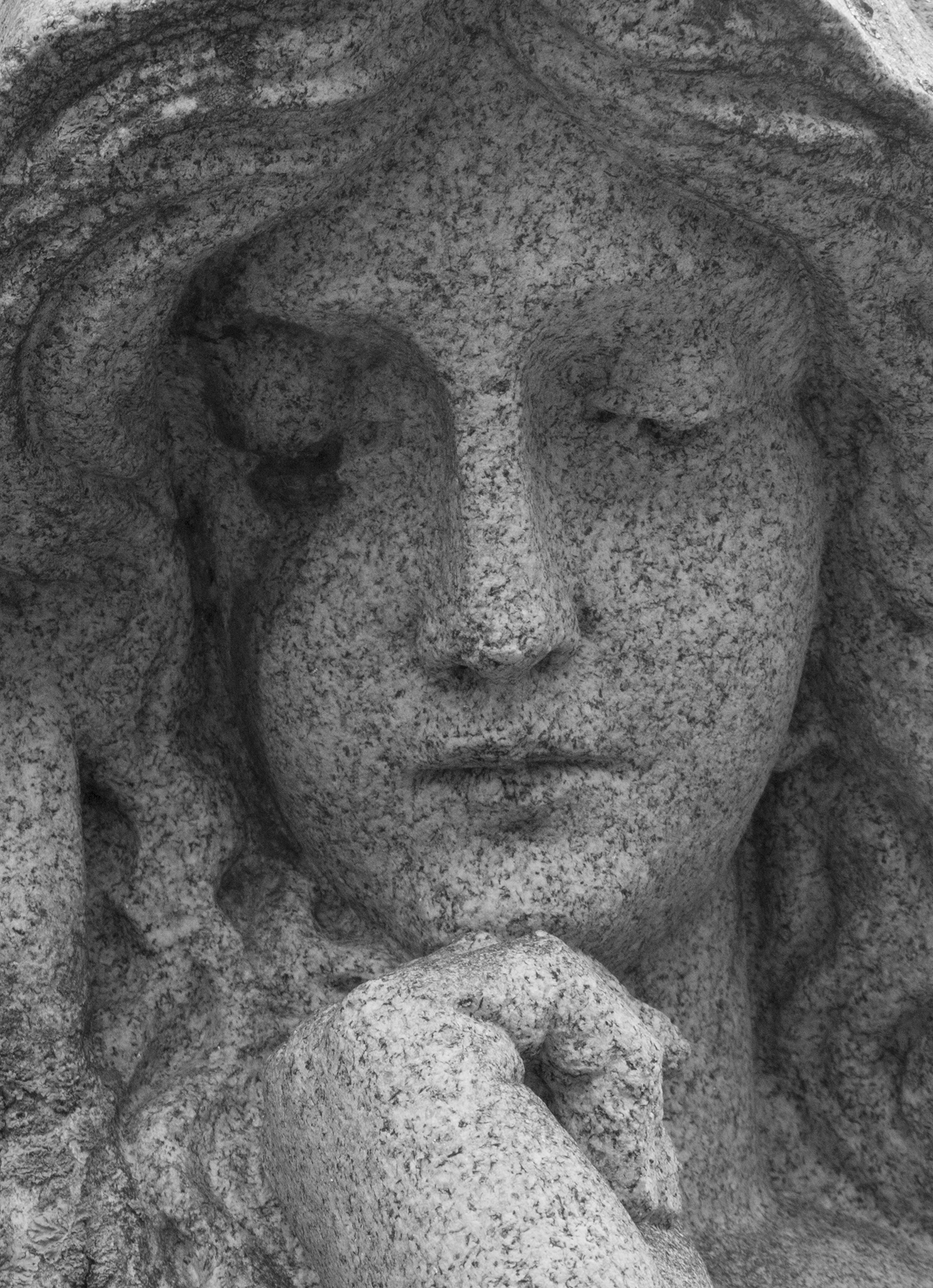 Close-up of the sorrowful face on a statue of a woman.