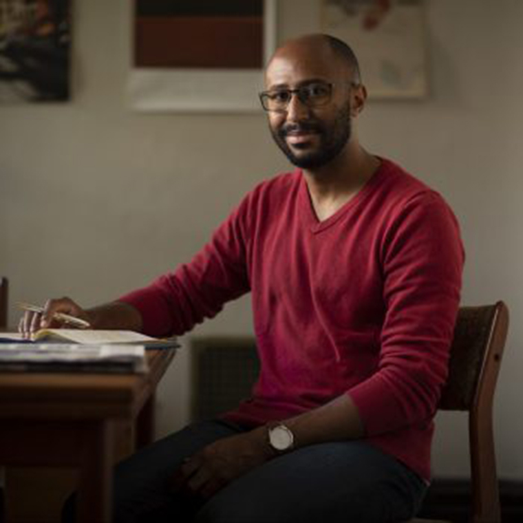 Photograph of Cameron Barnett seated at a desk.